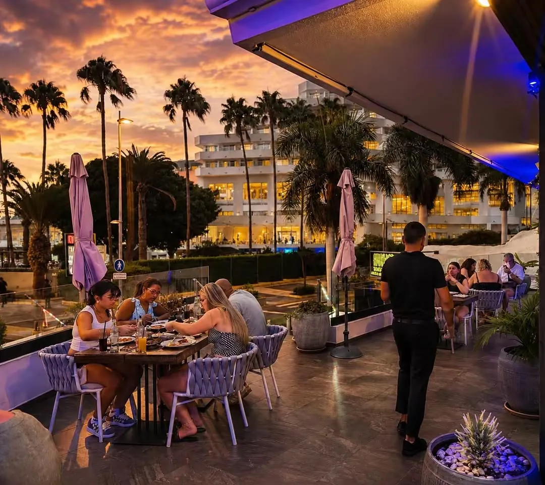 Guests dining on the Monsoon Tenerife terrace beneath an orange sunset