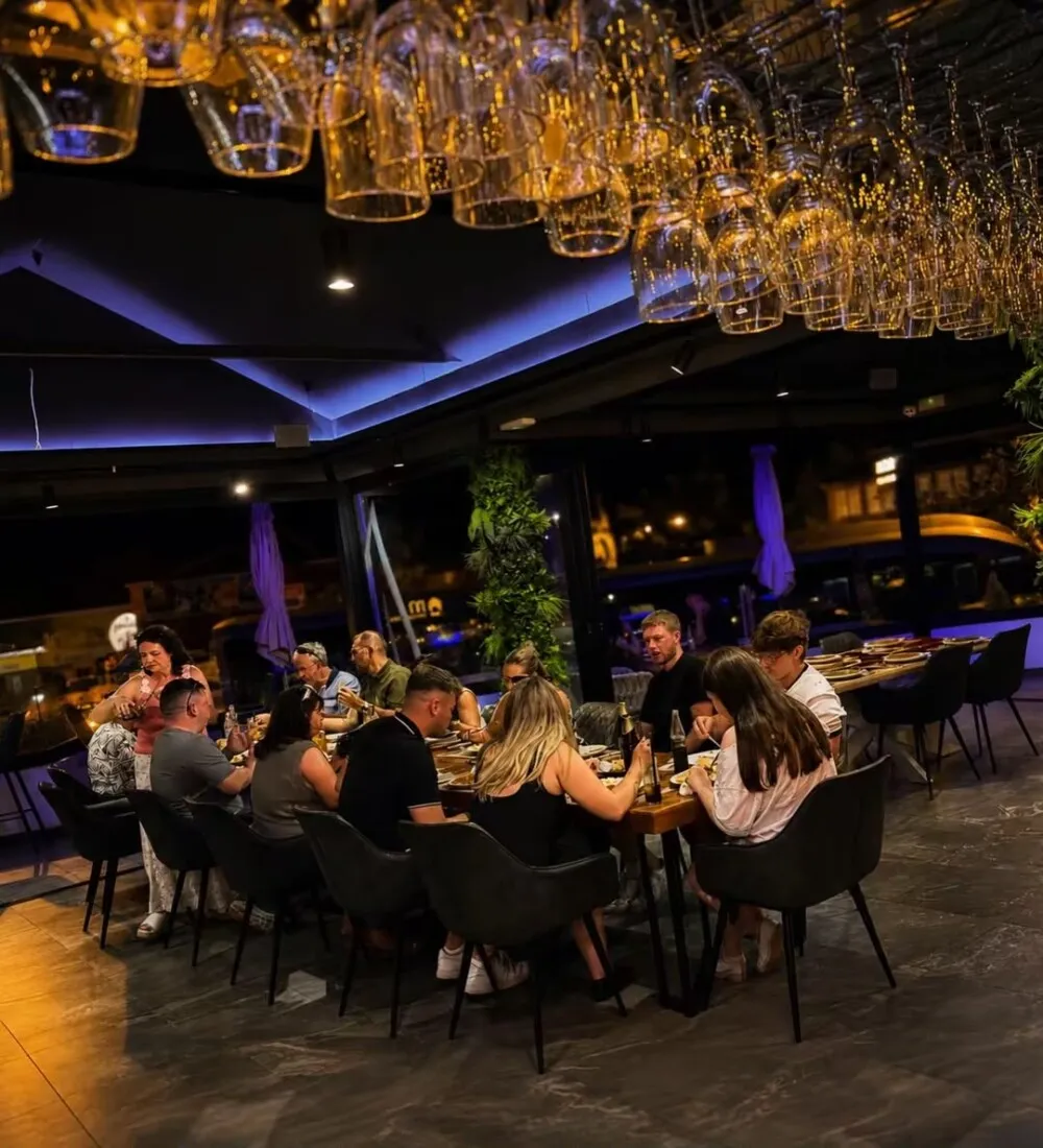 A group dining beneath hanging glassware at Monsoon Tenerife