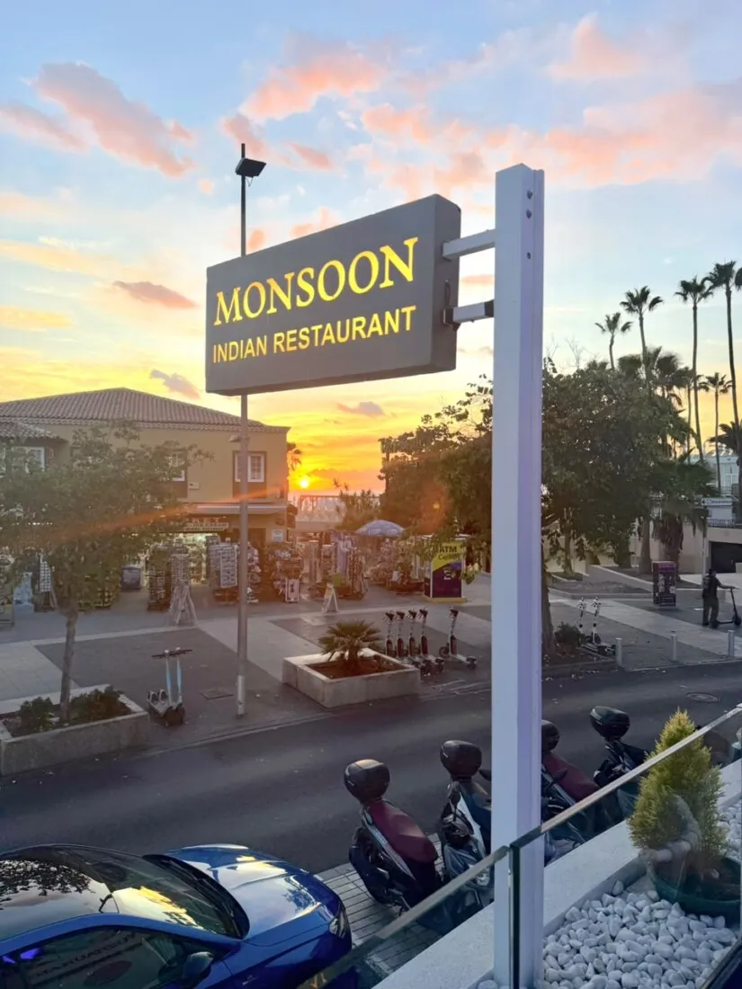 Monsoon Indian Restaurant street sign against a sunset